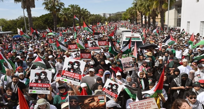 Protesters hold placards and Palestinian flags as they march through the city centre during a civil society and faith-based organizations’ mass rally for Gaza, in Cape Town on September 27, 2025. (Photo by RODGER BOSCH / AFP)